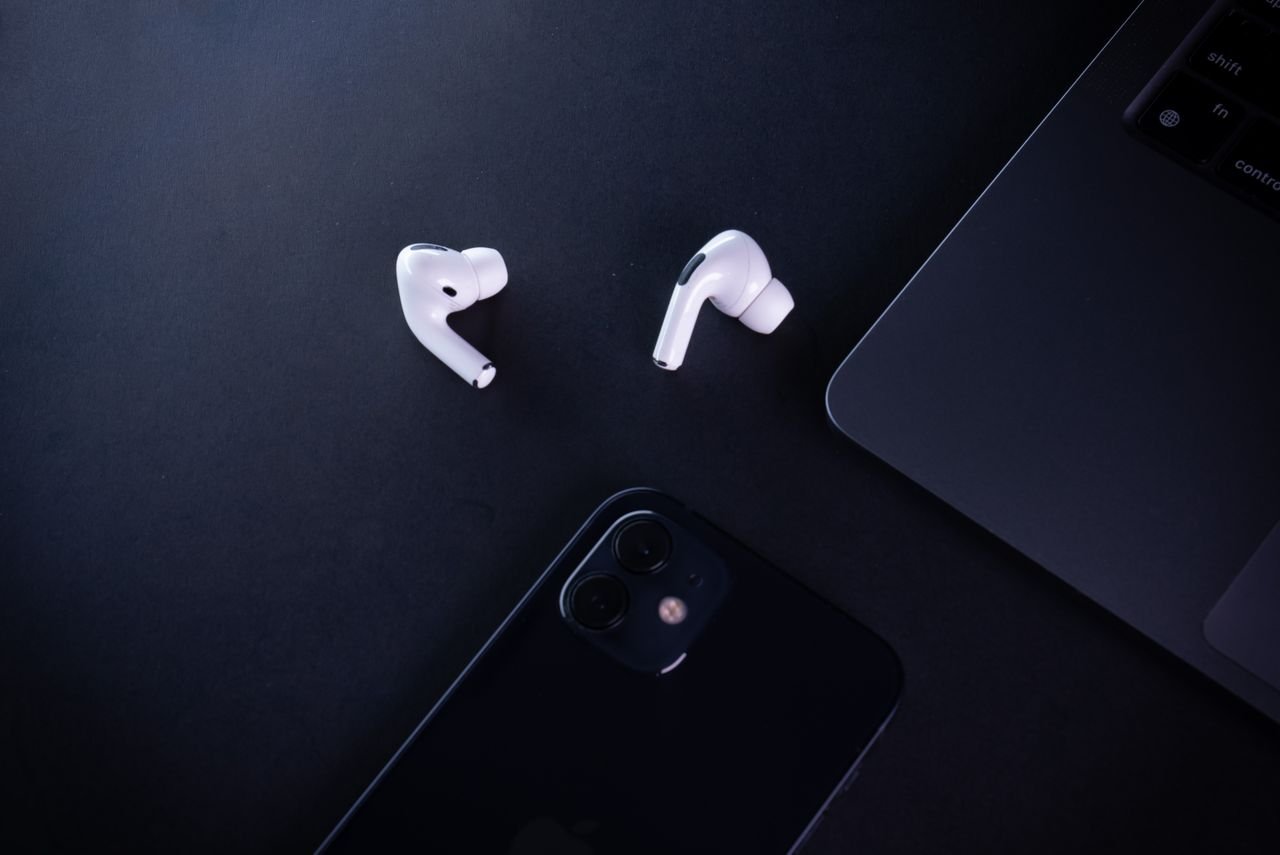 Minimalist workspace featuring earphones, smartphone, and laptop, perfect for tech lovers.